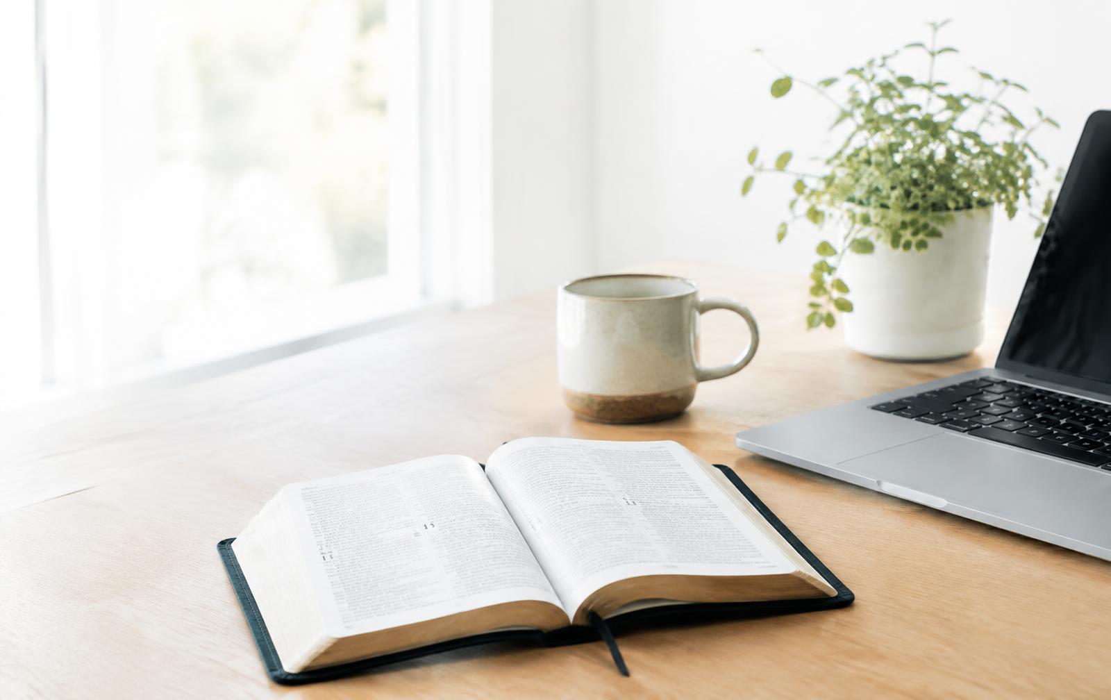 Open Bible beside a laptop